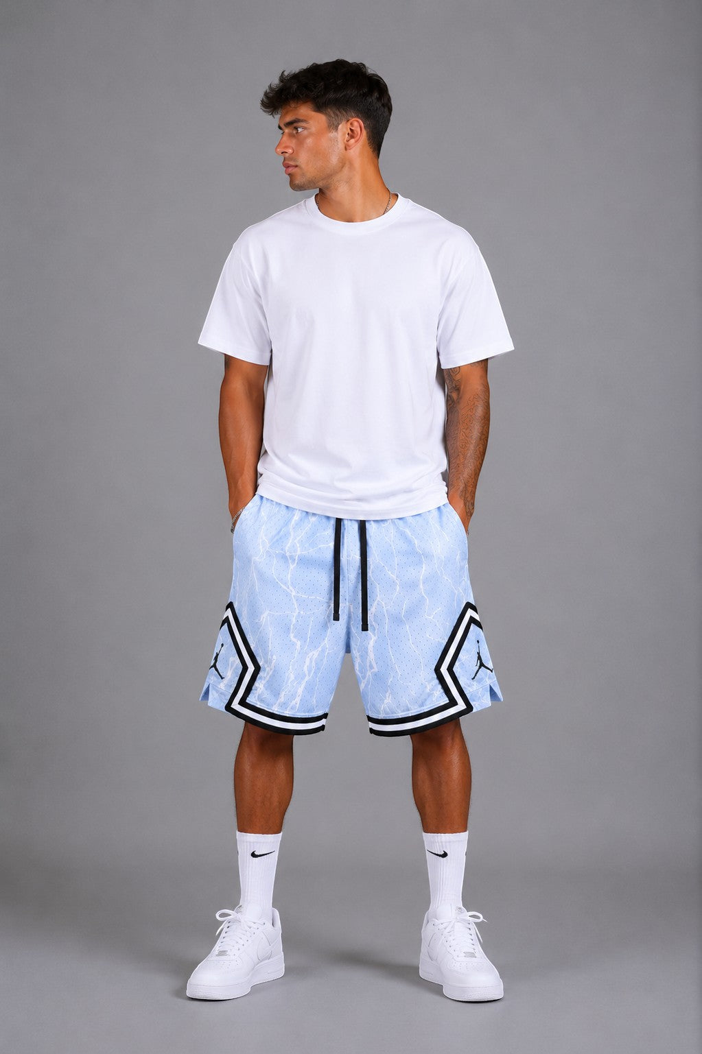 Hoopers light blue mesh basketball shorts with white lightning print and black trim. Model is wearing a white t-shirt and sneakers.