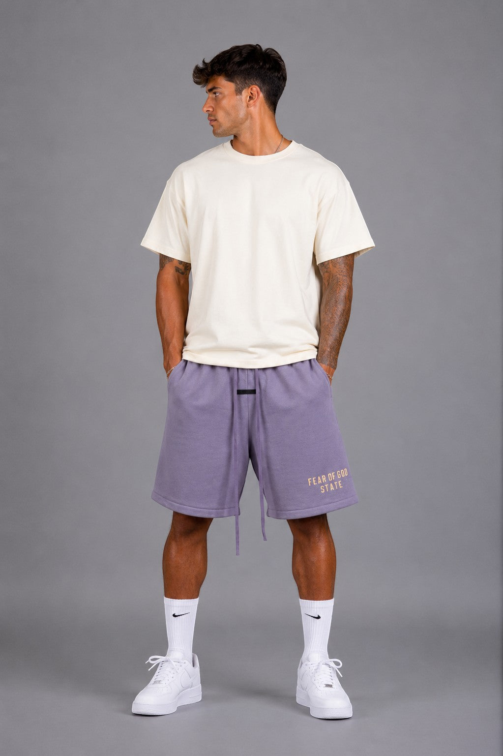 Hoopers lilac purple Fear Of God sweat shorts with drawstring and embroidered logo. Model wears cream t-shirt and white sneakers.