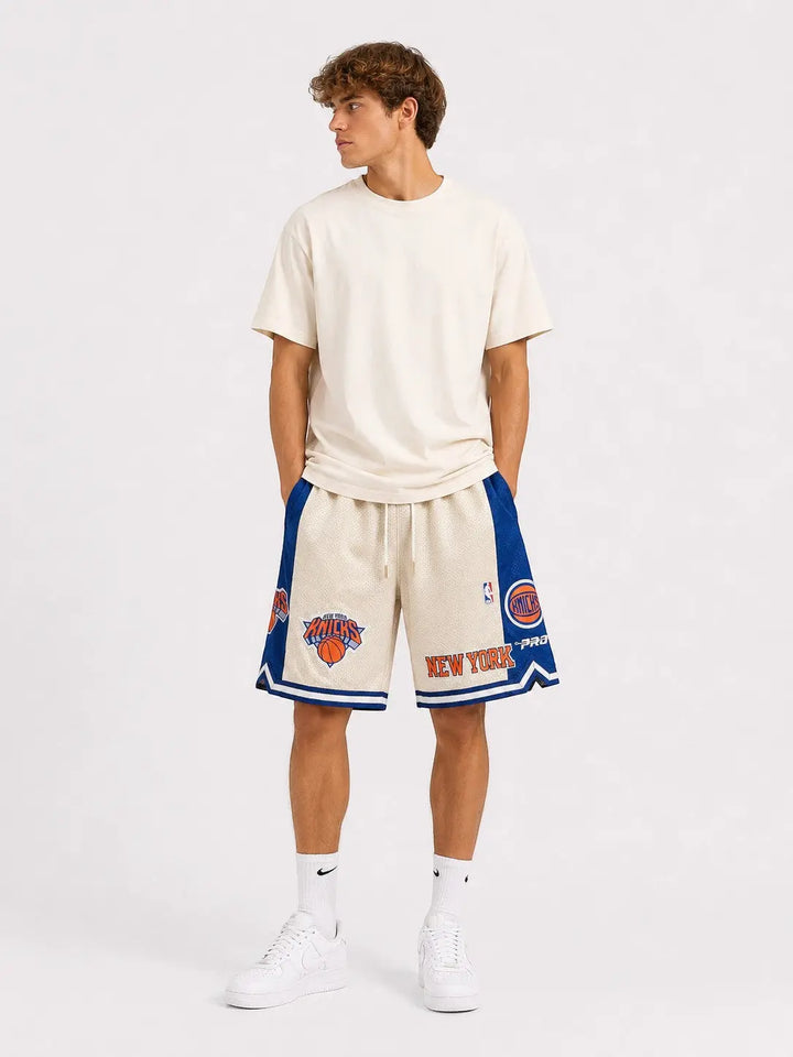 Hoopers New York Knicks retro basketball shorts in cream with blue and orange accents. Features embroidered logos and a wide fit.